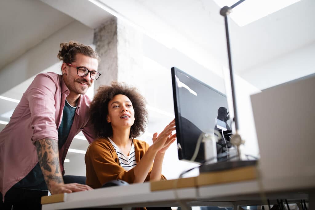 Creative managers point and smile at a computer screen.