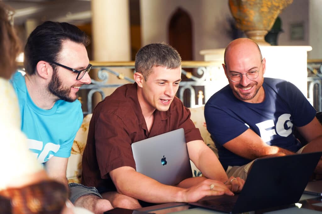 Three Publitas employees working on laptop and smiling.