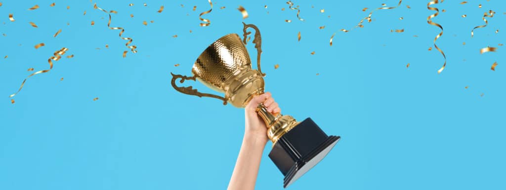 Hand holding a trophy on a blue background.